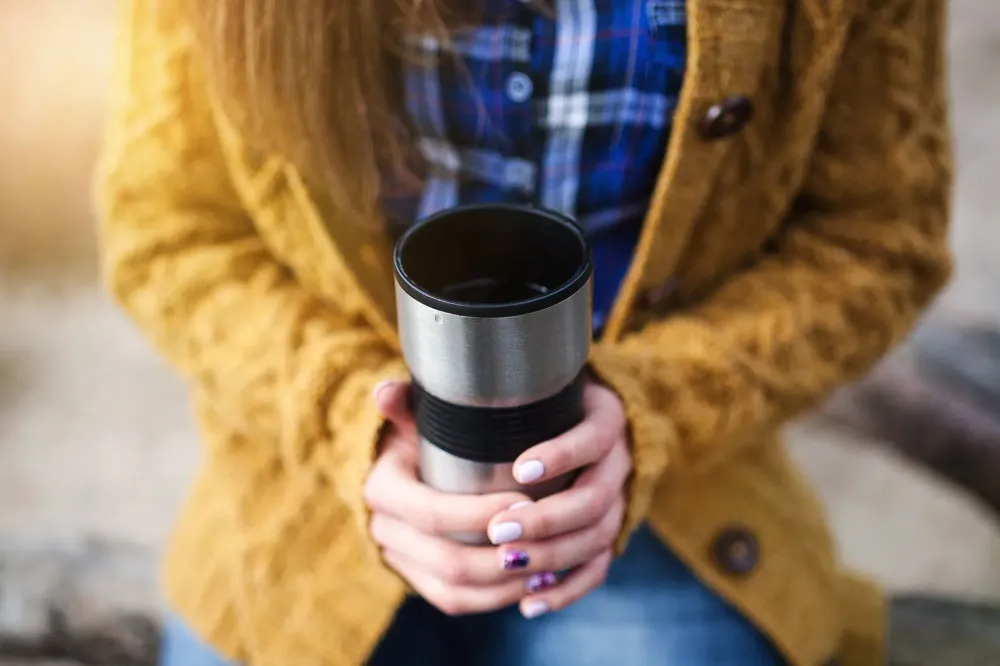 Woman holding hot travel mug of coffee